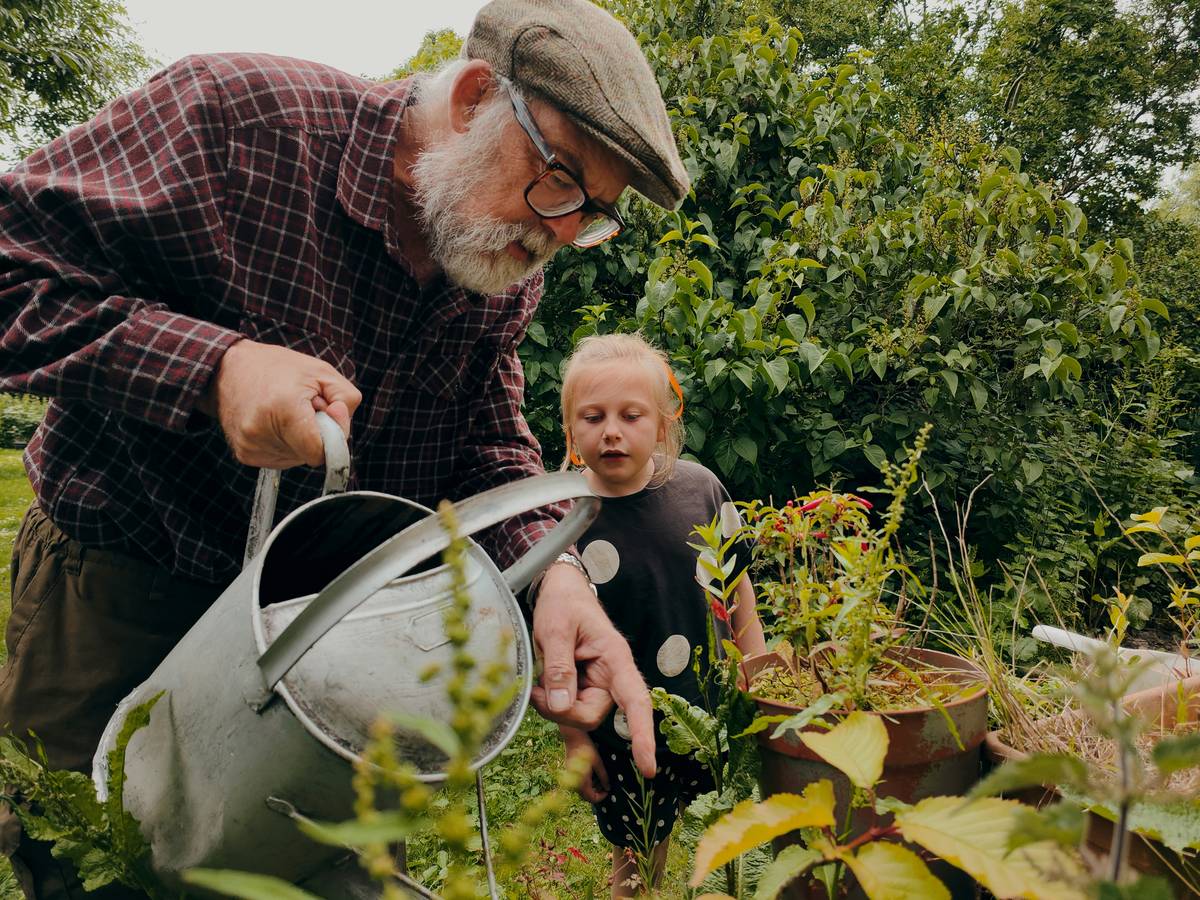 how to garden for beginners: a beginner planting herbs near a weather-resistant garden table