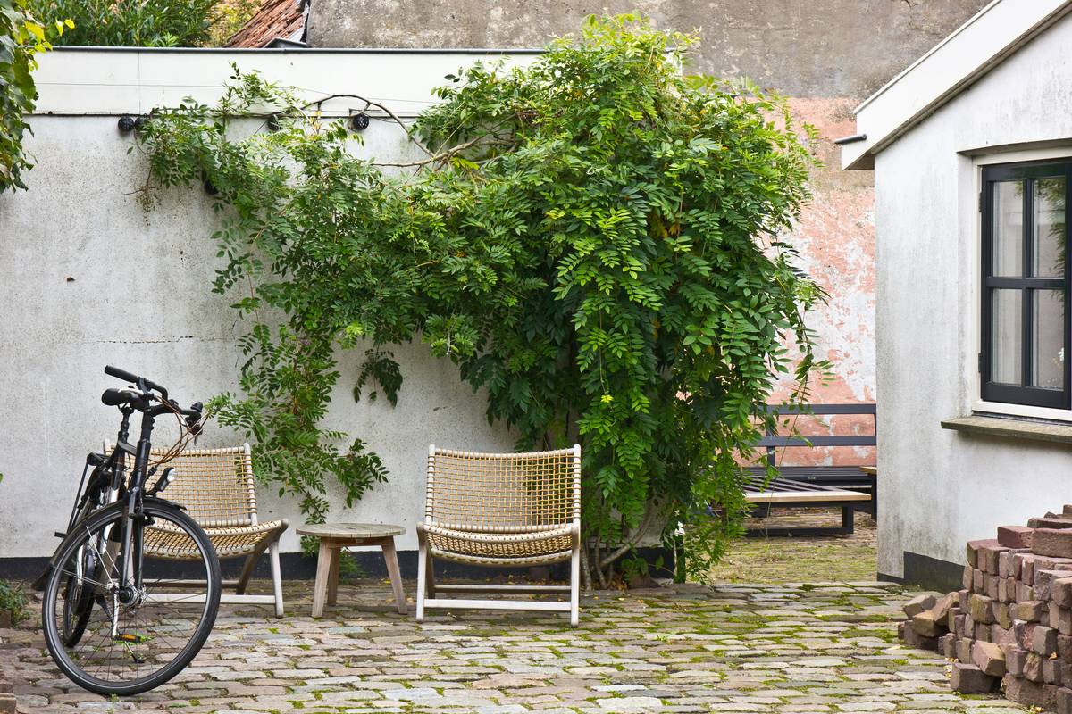 Small modern garden ideas featuring a sleek, compact garden table surrounded by potted herbs and string lights