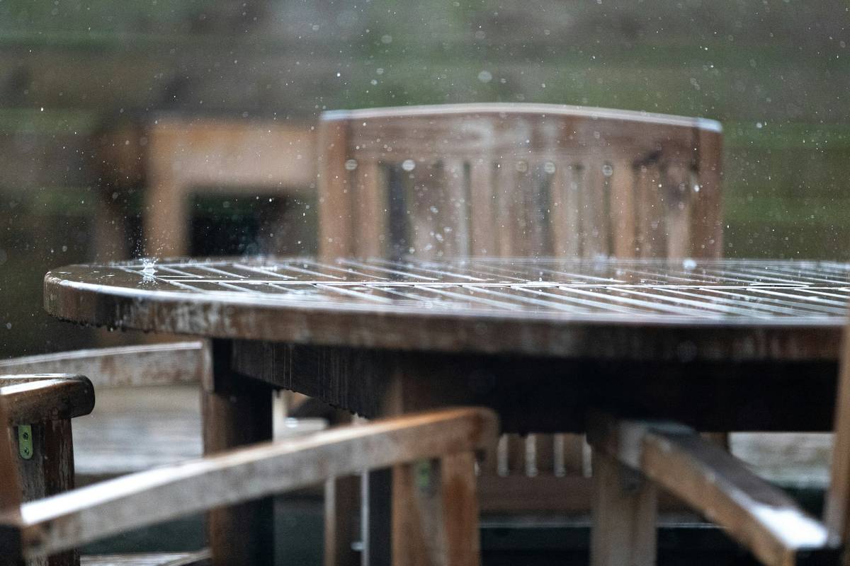easy care garden ideas featuring a weatherproof garden table with cover and potted herbs nearby