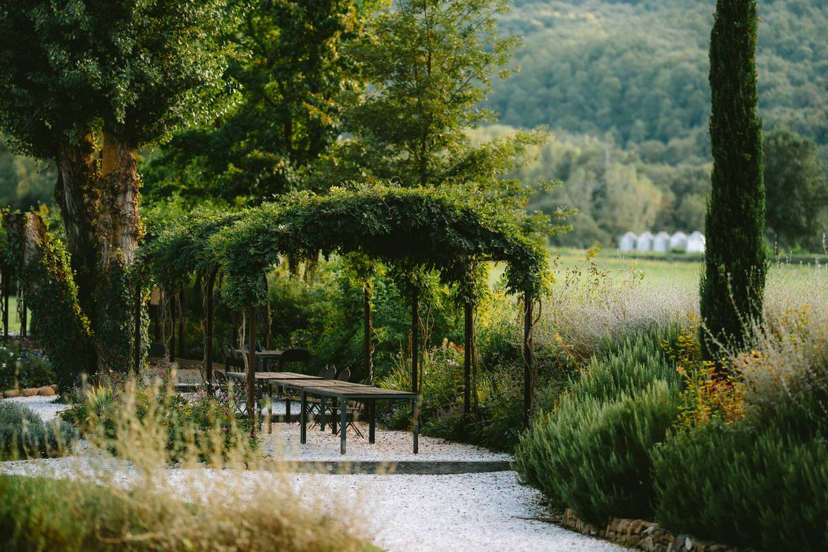 long garden design ideas with teak table under pergola surrounded by raised beds