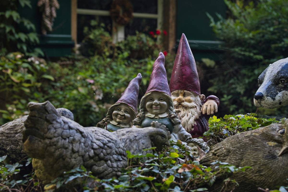 fairy garden table centerpiece ideas: miniature terracotta planter with moss, tiny stone pathway, and hand-painted ceramic fairy sitting beside a thimble-sized watering can on a weathered oak garden table